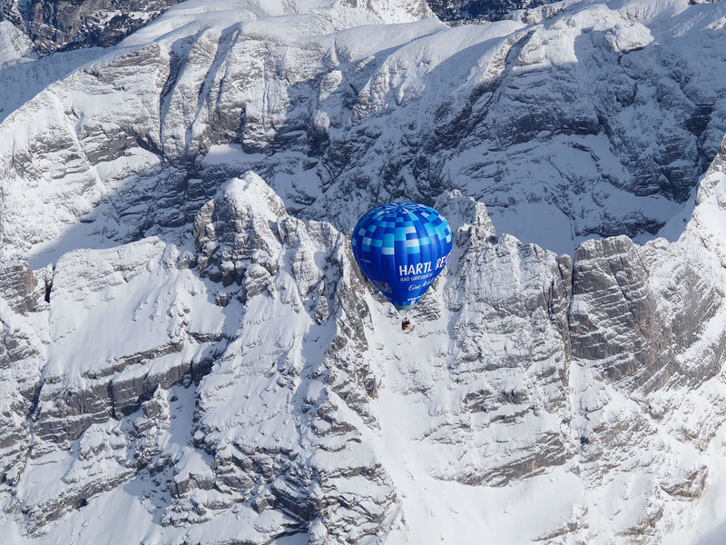 Blauer Ballon vor einer schneebedeckten Steilwand in den Bergen