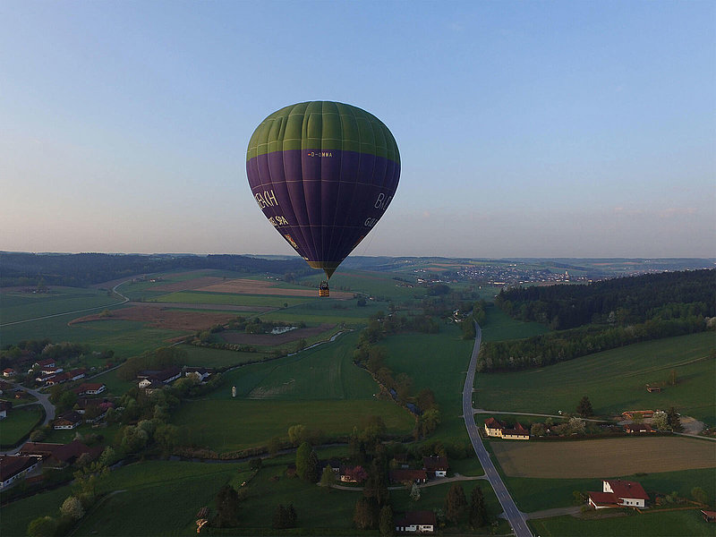 Heißluftballon gleitet über Felder, Straßen und vereinzelte Häuser