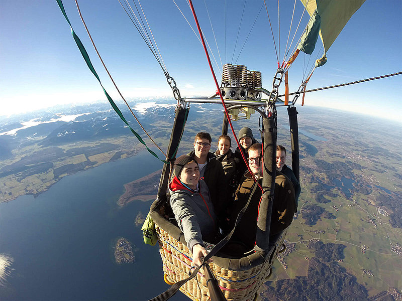 Selfie-Aufnahme der Passagiere mit Ballonfahrer Lukas über einem schönen See