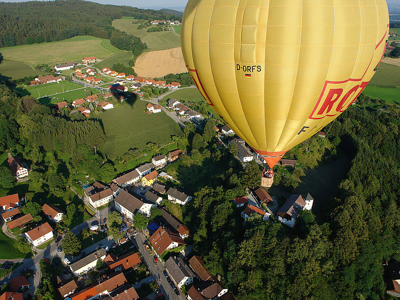 Gelber Ballon fliegt über eine kleine Stadt in Bayern