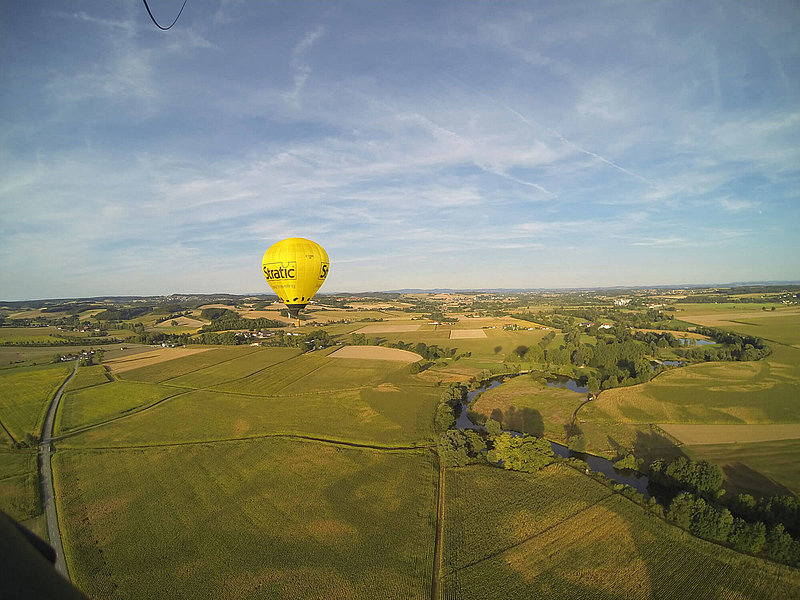 Heißluftballon fährt über grüne Wiesen und Felder 