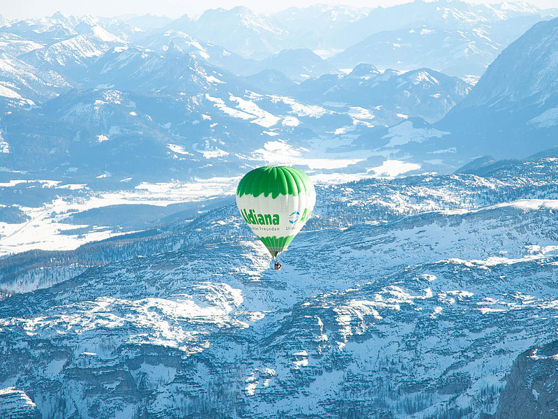 Grün-weißer Ballon vor einem spektakulären Alpenpanorama