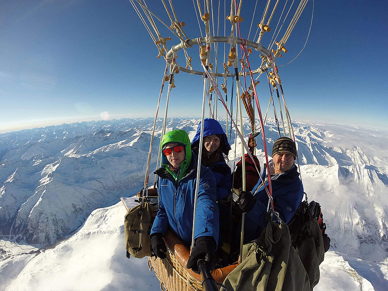 Kleiner Ballonkorb mit drei Passagieren über den Alpen 