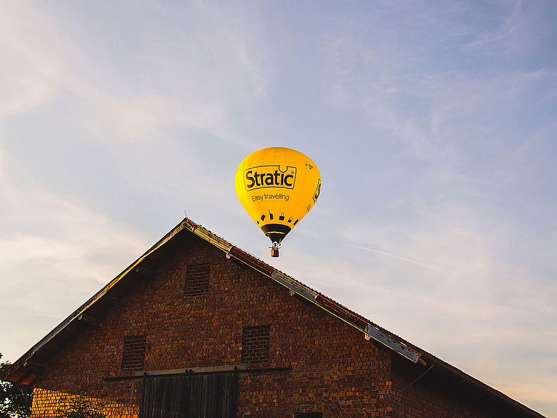 Heißluftballon über einer urigen Holzscheune in einem Dorf