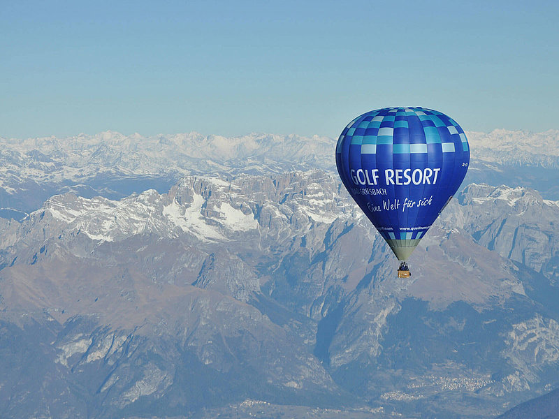 Blauer Ballon gleitet über schneebedeckte Berggipfel